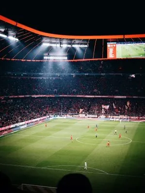 Packed football stadium at night viewed from stands during active match.